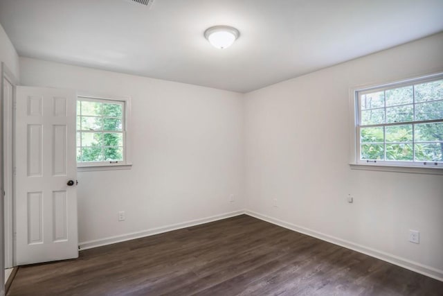 empty room with plenty of natural light, dark wood-style flooring, and baseboards