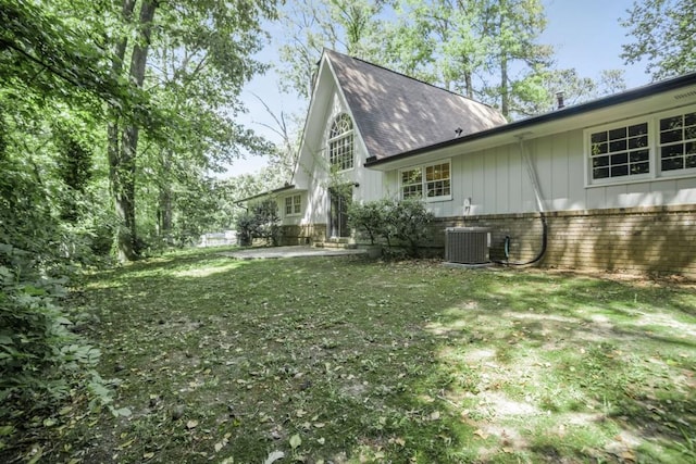 view of home's exterior featuring a shingled roof, central AC, and brick siding