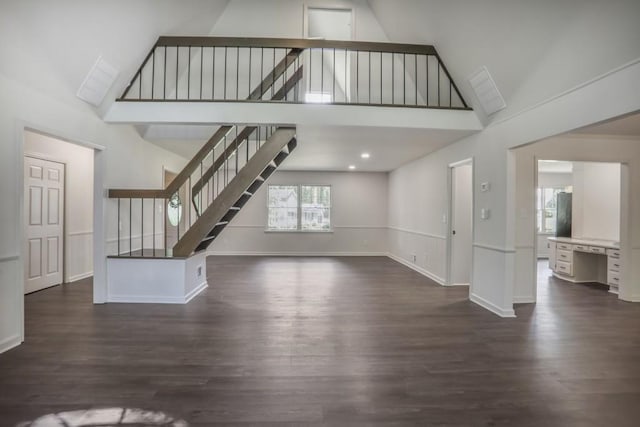 unfurnished living room with high vaulted ceiling, stairs, dark wood finished floors, and baseboards