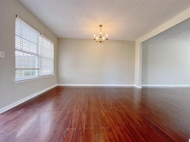 unfurnished room featuring a chandelier, a textured ceiling, and hardwood / wood-style flooring