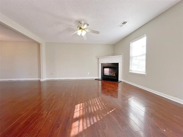 unfurnished living room featuring ceiling fan, hardwood / wood-style floors, and a textured ceiling