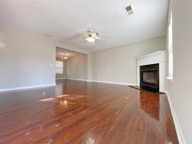 unfurnished living room featuring hardwood / wood-style flooring, ceiling fan with notable chandelier, and a textured ceiling