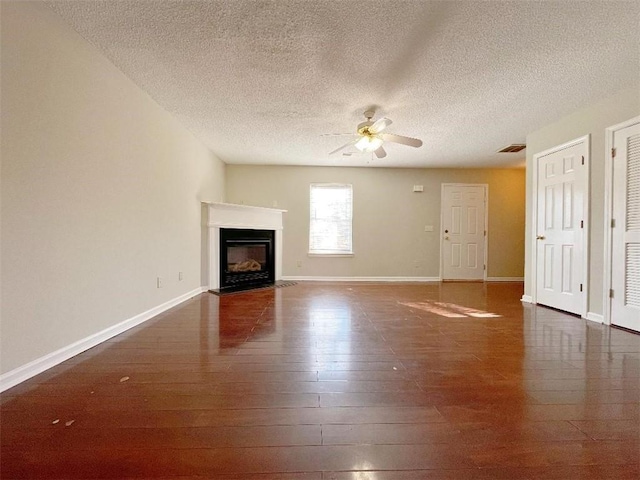 unfurnished living room with dark hardwood / wood-style floors, ceiling fan, and a textured ceiling