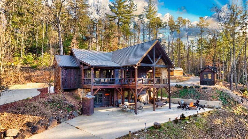 view of front facade with a fire pit, metal roof, a wooden deck, a patio area, and a wooded view