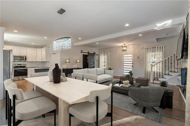 dining room featuring a chandelier, light hardwood / wood-style floors, and a barn door