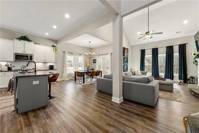 interior space with open floor plan, stainless steel microwave, a sink, and dark wood-style floors