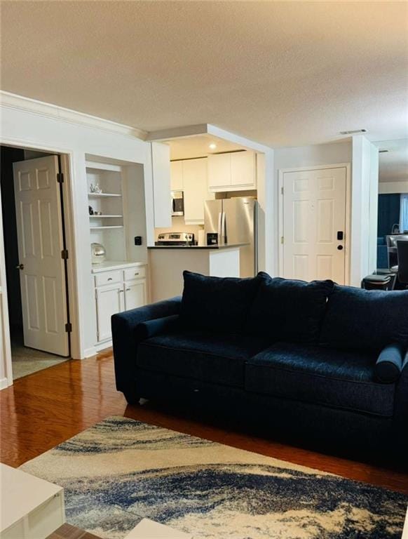 living room with a textured ceiling, built in features, and wood finished floors