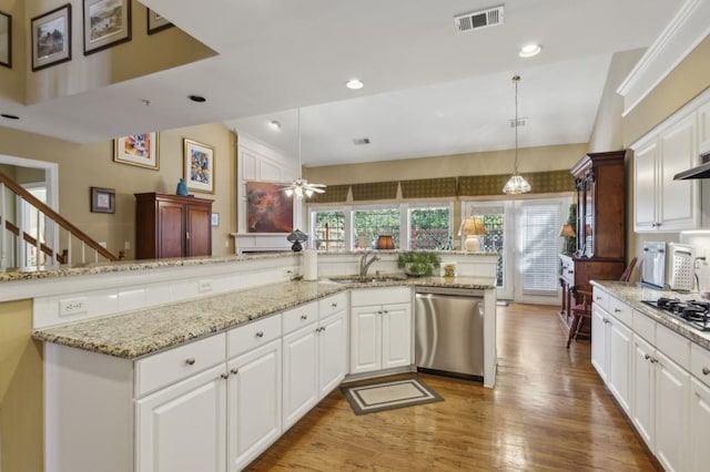 kitchen featuring stainless steel dishwasher, white cabinetry, hanging light fixtures, and a wealth of natural light