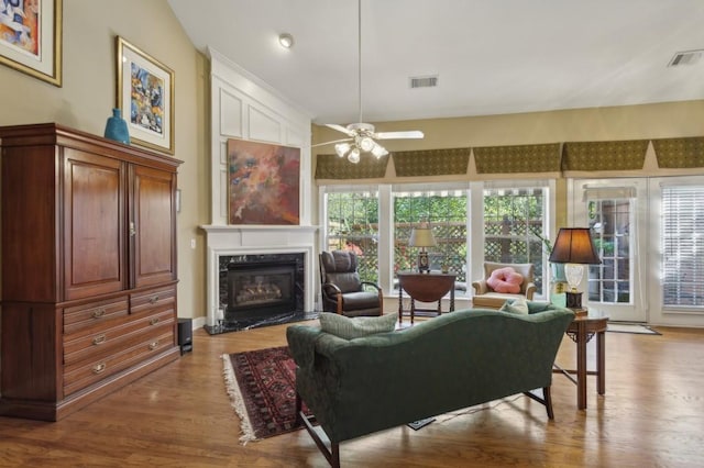 living room with a premium fireplace, vaulted ceiling, light hardwood / wood-style floors, and ceiling fan