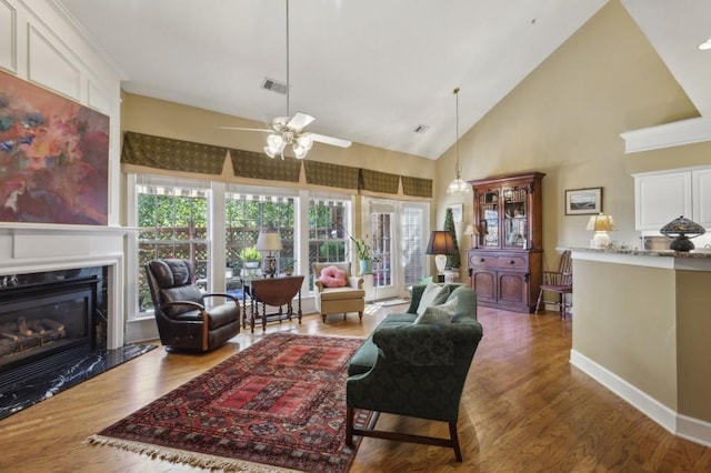 living room with a premium fireplace, wood-type flooring, high vaulted ceiling, and ceiling fan