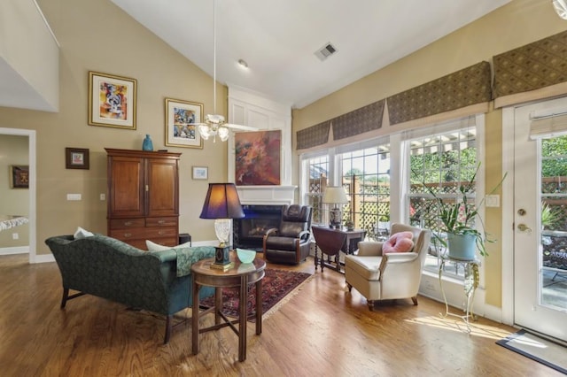 living area with high vaulted ceiling, a wealth of natural light, and hardwood / wood-style floors