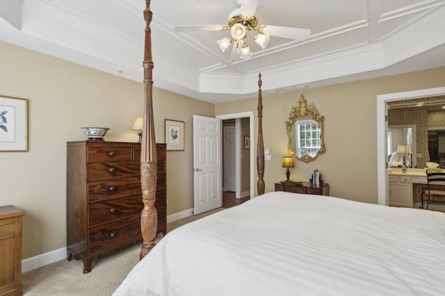 bedroom with ceiling fan, a raised ceiling, ensuite bathroom, and light carpet