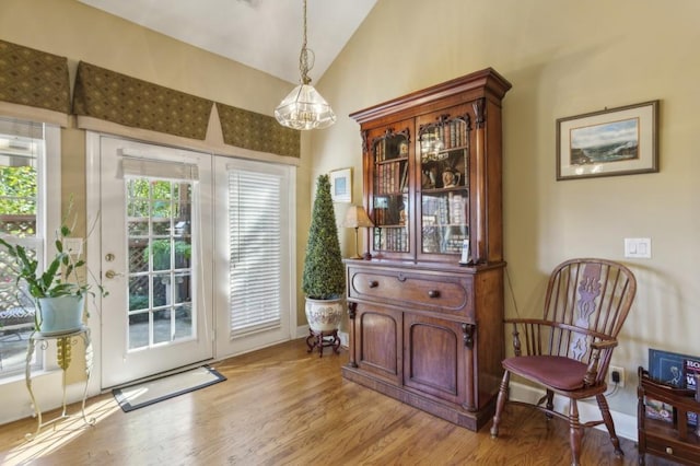 entryway with vaulted ceiling, a notable chandelier, and light hardwood / wood-style floors