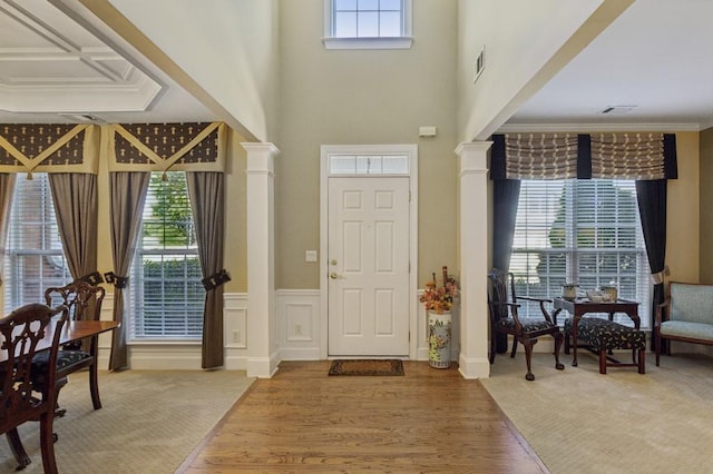 foyer entrance with a healthy amount of sunlight, wood-type flooring, and decorative columns