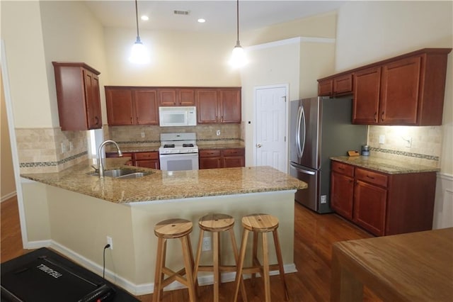 kitchen with kitchen peninsula, pendant lighting, white appliances, light stone countertops, and a high ceiling