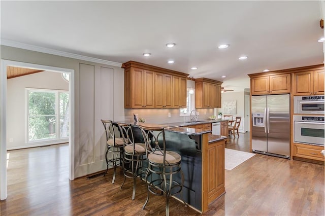 4246 Stilson Cir, Peachtree Corners, GA 30092 - kitchen with appliances with stainless steel finishes, a sink, ornamental molding, a kitchen breakfast bar, and brown cabinetry