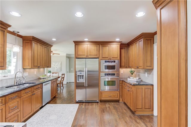4246 Stilson Cir, Peachtree Corners, GA 30092 - kitchen featuring stainless steel appliances, a sink, brown cabinets, dark stone counters, and backsplash