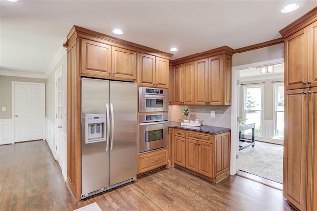 4246 Stilson Cir, Peachtree Corners, GA 30092 - kitchen featuring appliances with stainless steel finishes, ornamental molding, wood finished floors, dark stone counters, and a decorative wall
