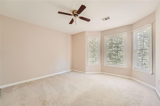 carpeted empty room with a wealth of natural light and ceiling fan