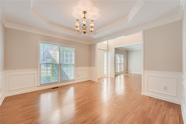 empty room featuring plenty of natural light, a chandelier, and a tray ceiling