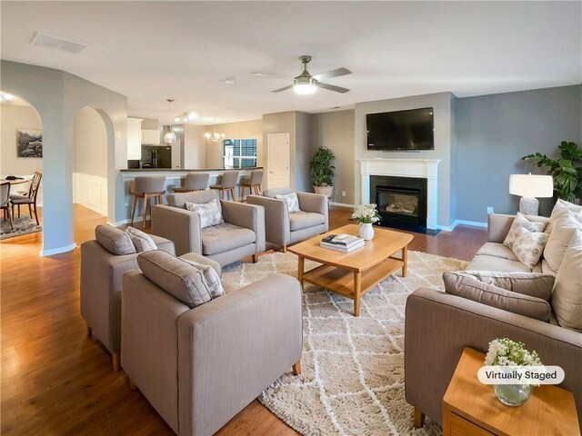 living room with hardwood / wood-style flooring and ceiling fan with notable chandelier