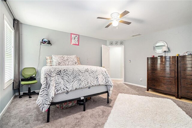 carpeted bedroom featuring multiple windows and ceiling fan