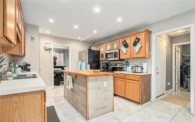 kitchen with a center island, light tile patterned floors, stainless steel appliances, and sink