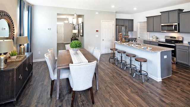 dining space featuring sink, dark hardwood / wood-style flooring, and an inviting chandelier