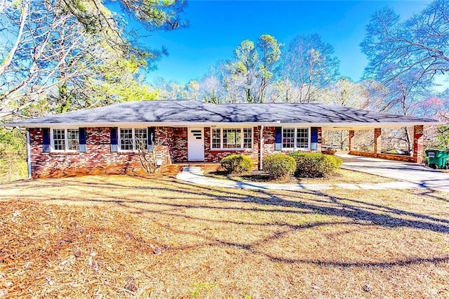 ranch-style home featuring a carport, a front yard, concrete driveway, and brick siding