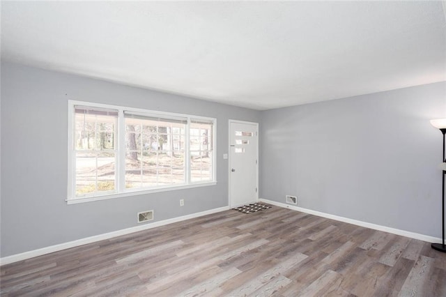 empty room featuring baseboards, visible vents, and wood finished floors