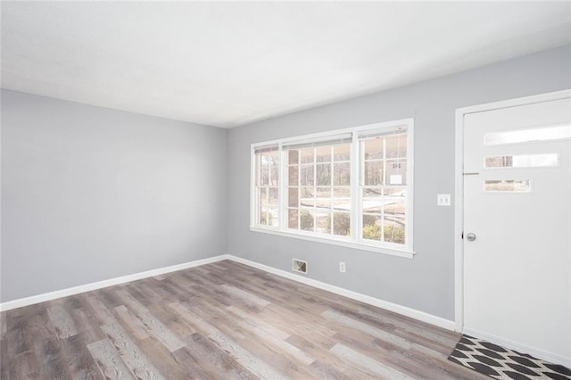 spare room featuring visible vents, baseboards, and wood finished floors