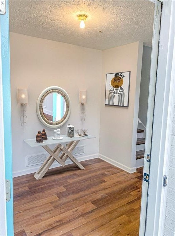 foyer entrance with a textured ceiling and dark hardwood / wood-style floors