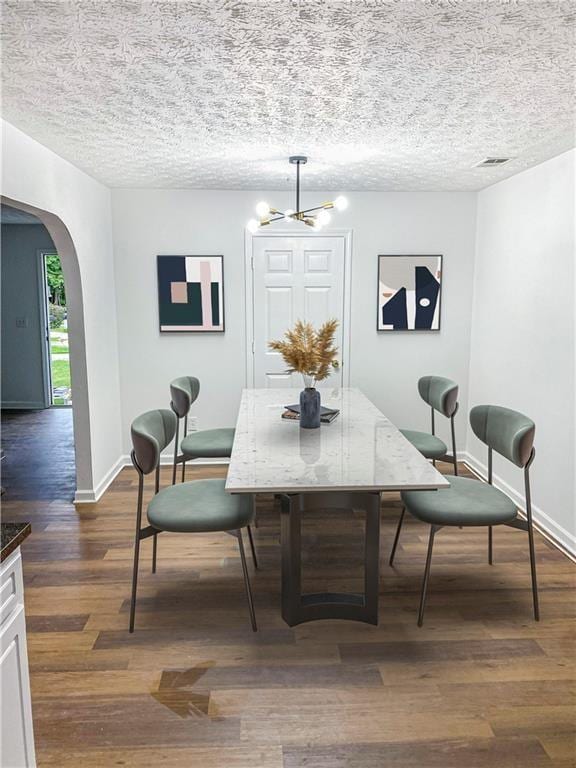 dining area featuring a textured ceiling, dark hardwood / wood-style flooring, and a notable chandelier