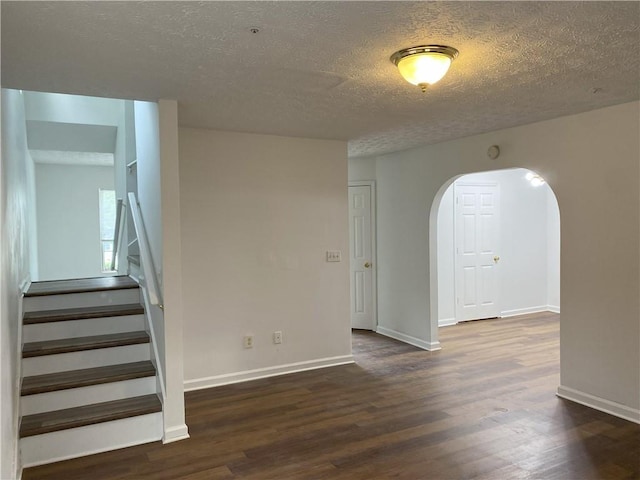 unfurnished room featuring a textured ceiling and dark hardwood / wood-style floors