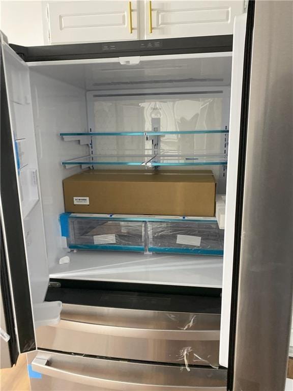 interior details featuring white cabinetry and fridge