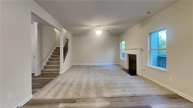 unfurnished living room with ceiling fan and dark wood-type flooring