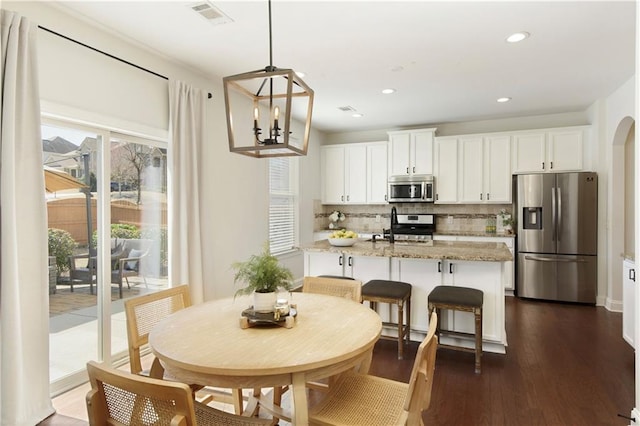 dining room featuring visible vents, dark wood-style floors, recessed lighting, arched walkways, and a notable chandelier