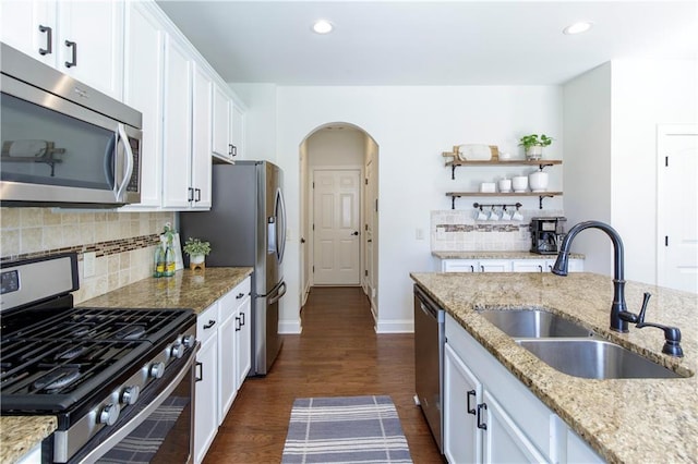 kitchen featuring dark wood-type flooring, a sink, white cabinetry, stainless steel appliances, and arched walkways