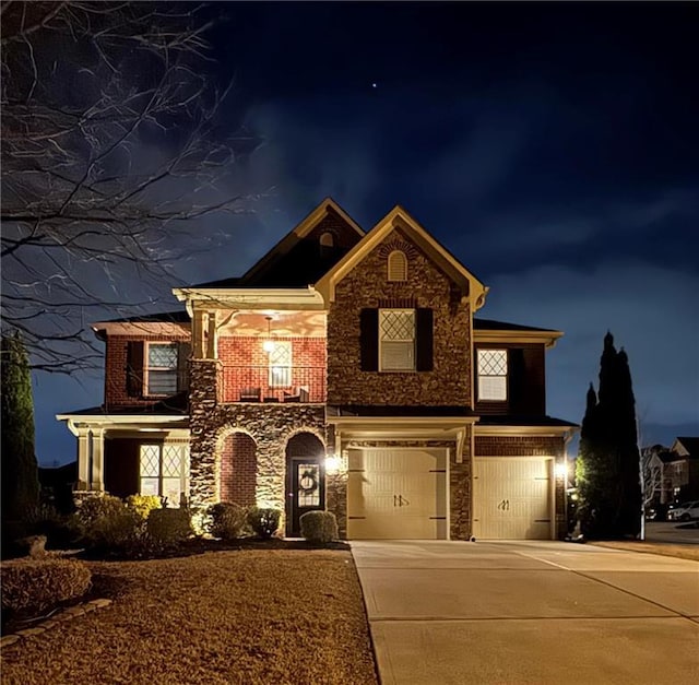 view of front facade featuring stone siding, a garage, concrete driveway, and a balcony