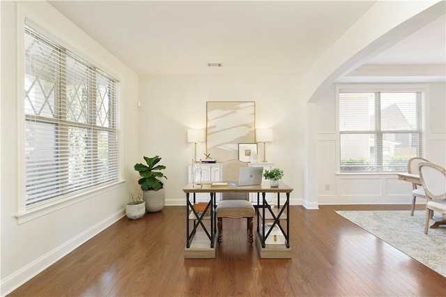 home office featuring visible vents, arched walkways, wood-type flooring, and baseboards