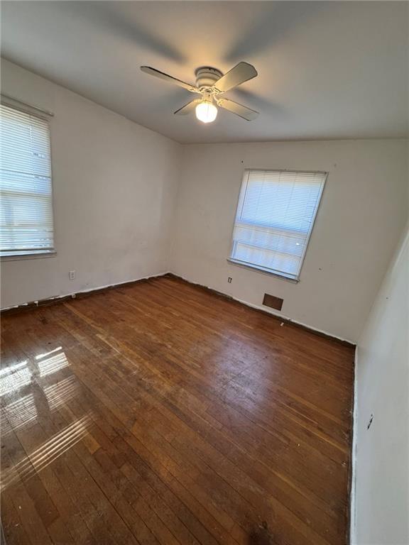 unfurnished room featuring dark wood-type flooring and ceiling fan