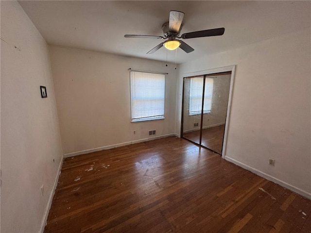 unfurnished bedroom with dark hardwood / wood-style floors, ceiling fan, and a closet