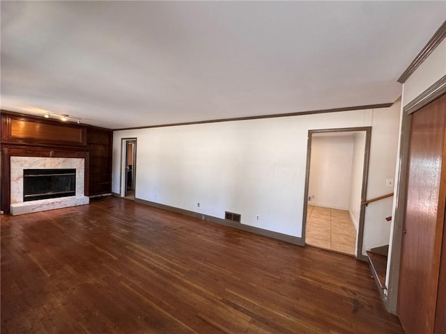 unfurnished living room with a fireplace, ornamental molding, dark hardwood / wood-style floors, and rail lighting