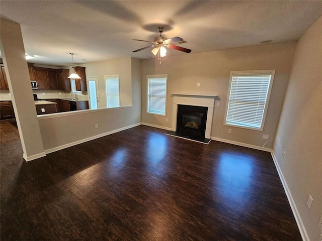 1021 Rock Elm Dr, Auburn, GA 30011 - unfurnished living room with dark wood-type flooring, plenty of natural light, a glass covered fireplace, and a ceiling fan
