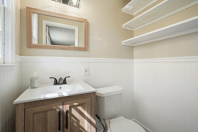 bathroom featuring vanity, toilet, and wainscoting