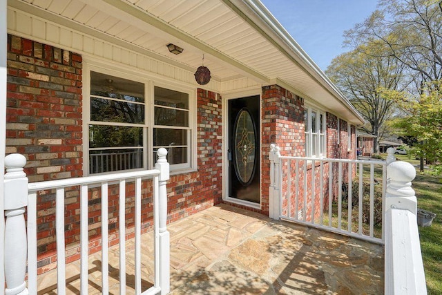 entrance to property with brick siding and a porch