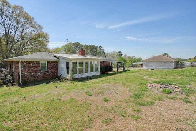 back of property with a chimney, brick siding, fence, and a lawn