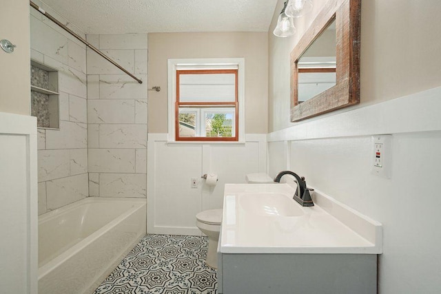 full bath featuring a wainscoted wall, a textured ceiling, toilet, vanity, and shower / tub combination