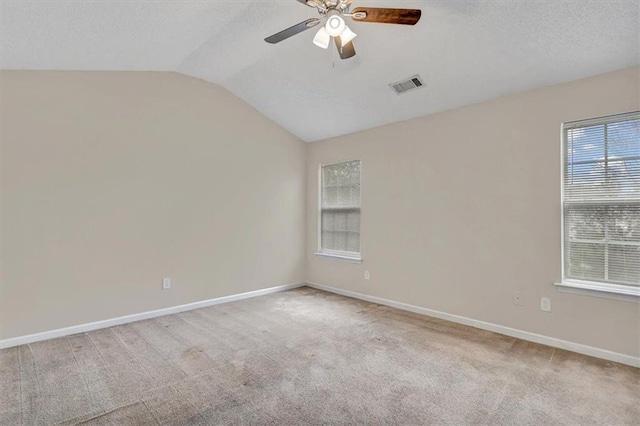 carpeted empty room with lofted ceiling, a textured ceiling, and ceiling fan