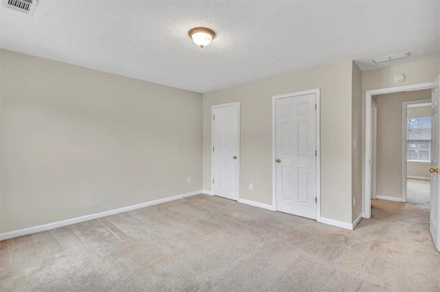 unfurnished bedroom featuring light colored carpet and a textured ceiling